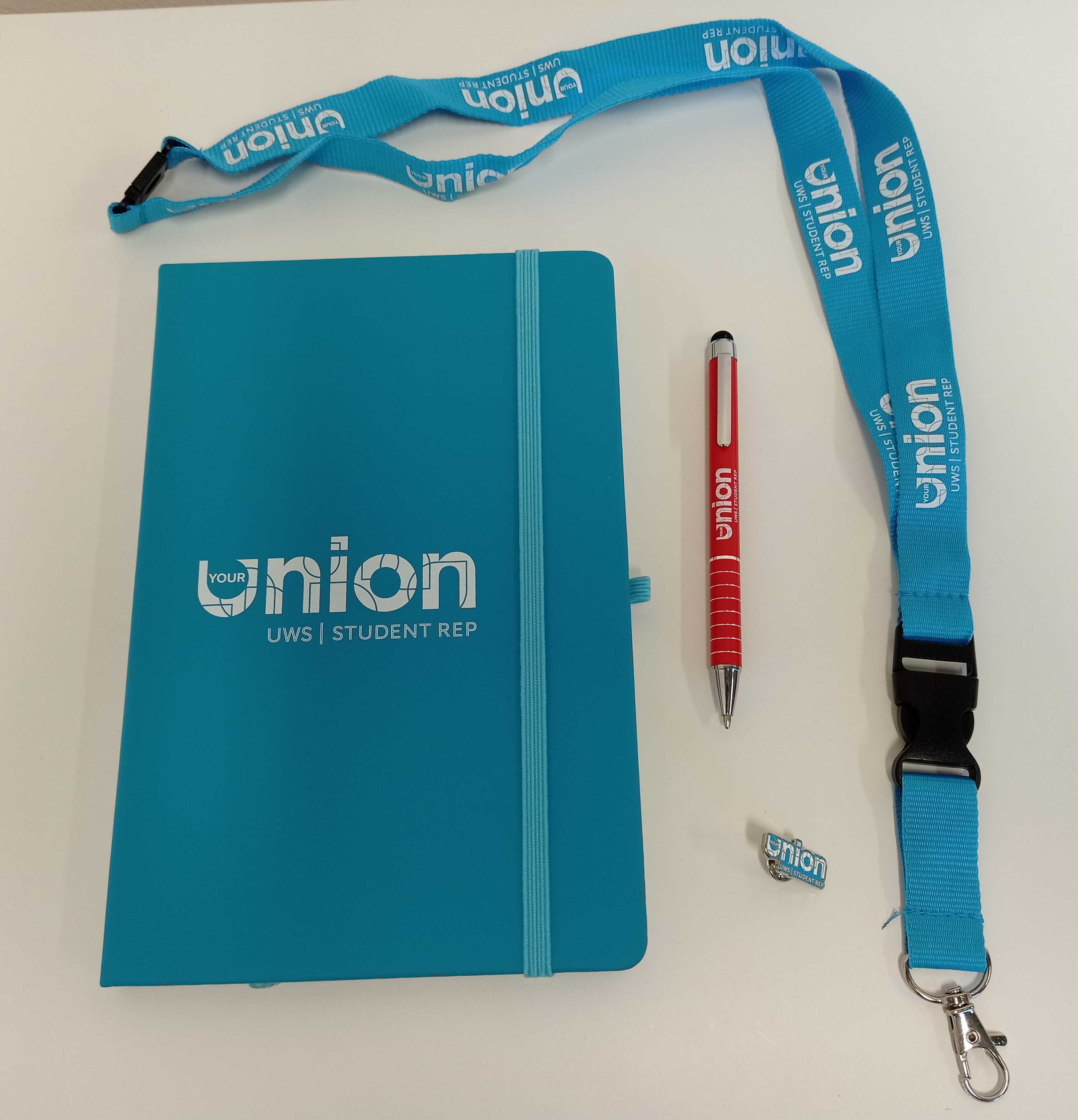 An Image of student Union student rep branded notebook, pen, lanyard, and pin badge